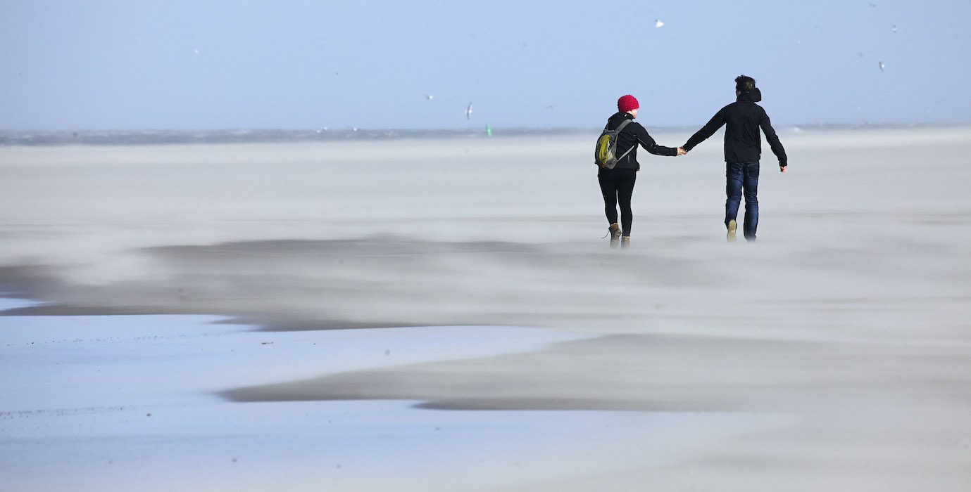 Couple is walking on the Dutch beach