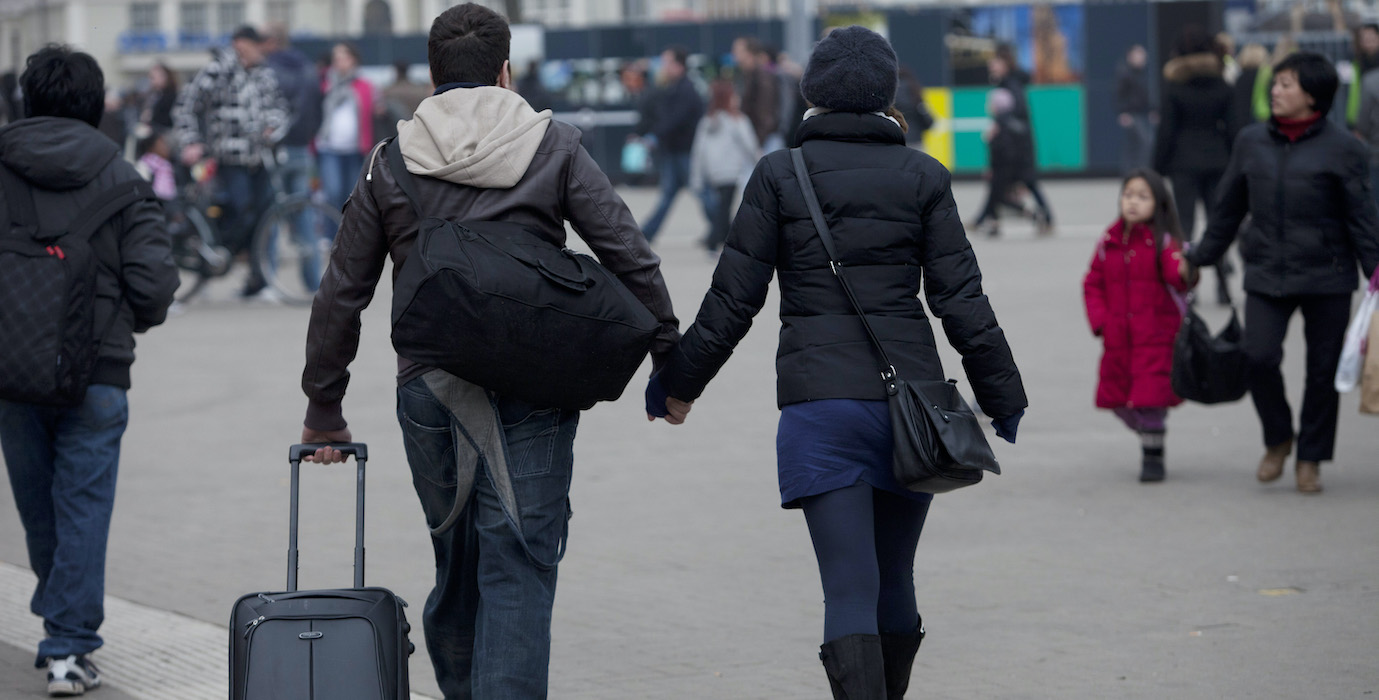 People walking with their suitcase in the city. 