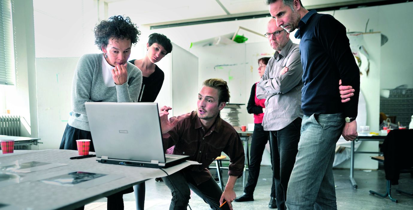 A goup of students watching a laptop and discuss their project. 