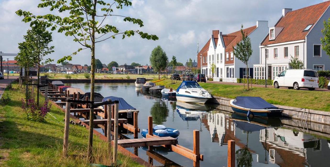 Water with boats and Dutch houses at the waterfront. 