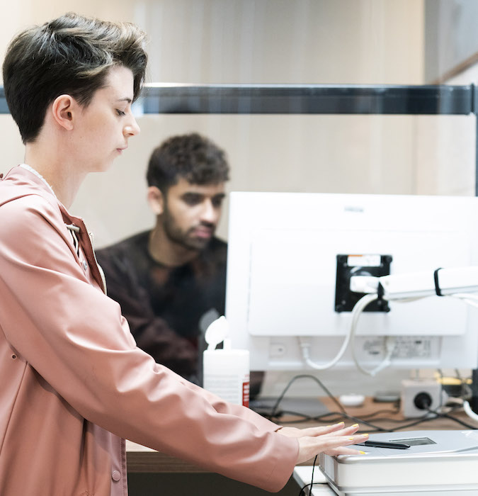  Two men are working behind a computer at the immigration and naturalisation service