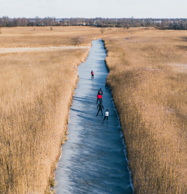 Winter landscape with persons ice skating. 