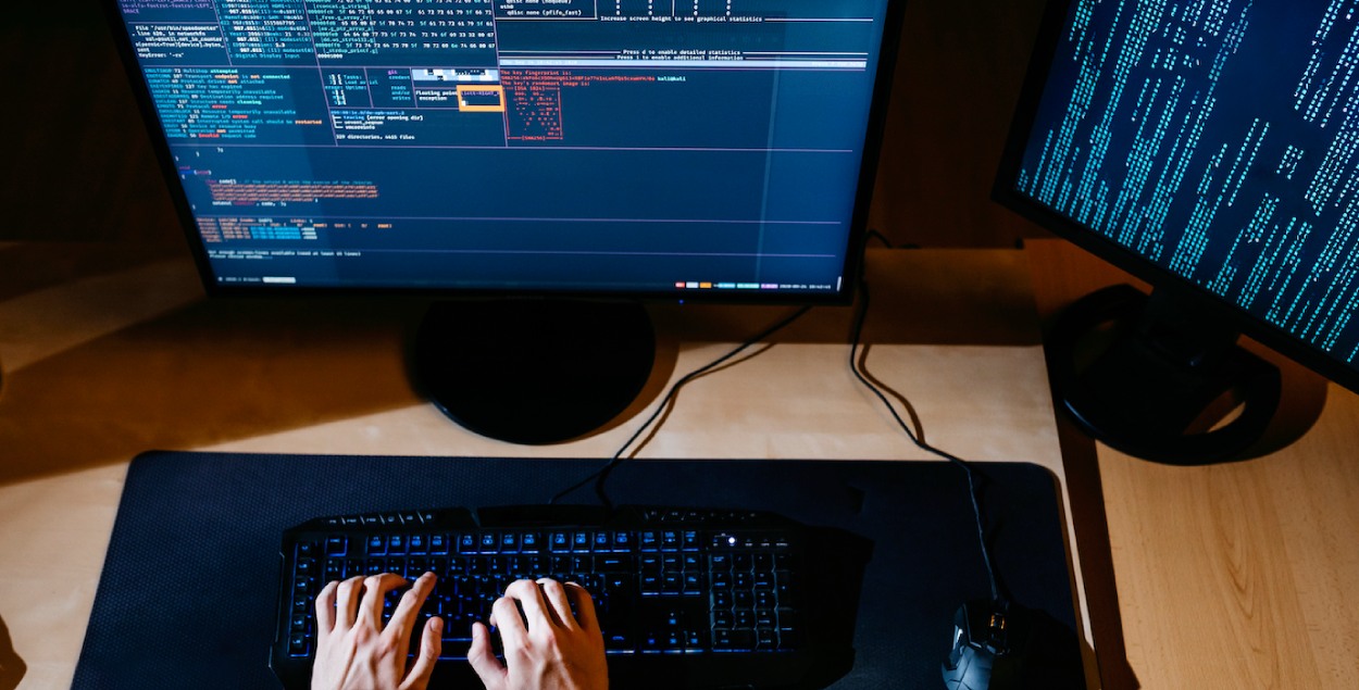 A person working at cyber security behind two computer screens. 