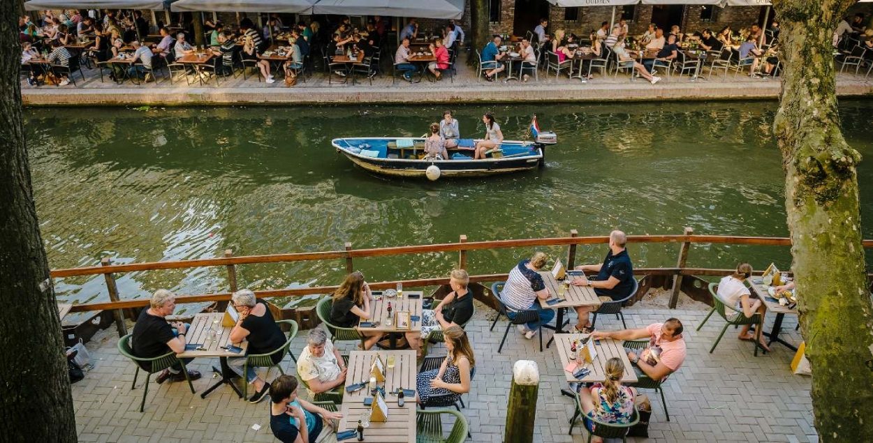 People sitting on a terrace at the waterfront in Utrecht. 