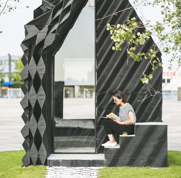 Women sitting on stairs of a modern building while reading a book. 