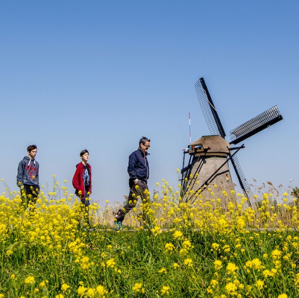 Dutch landscape with a windmill and a family that's enjoying a walk. 