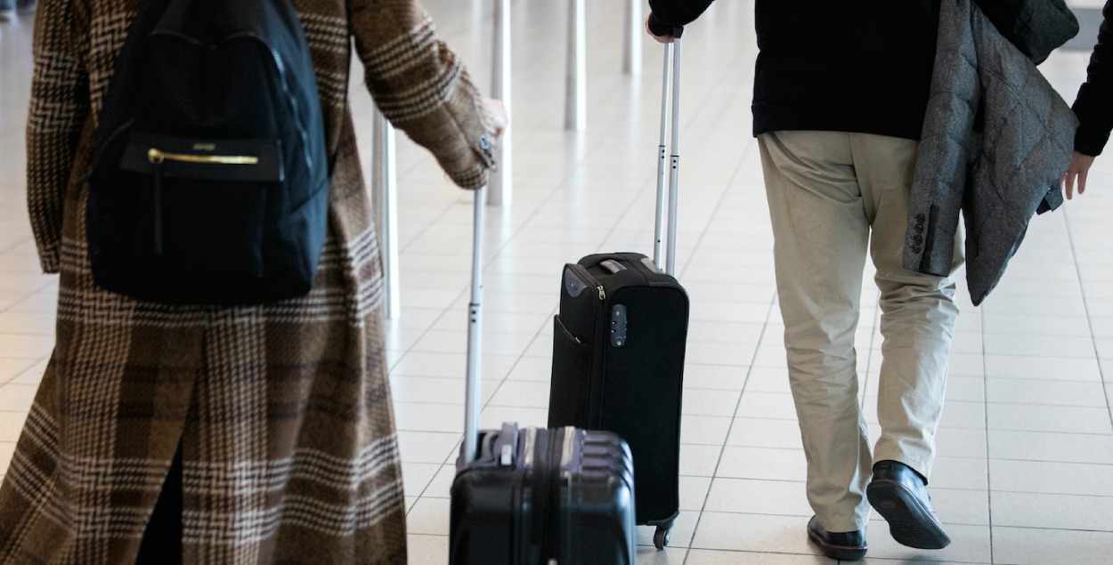 Two people with a suitcase at the airport. 