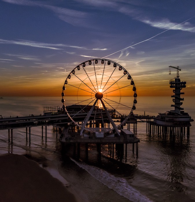 A ferris wheel at the beach during sunset.