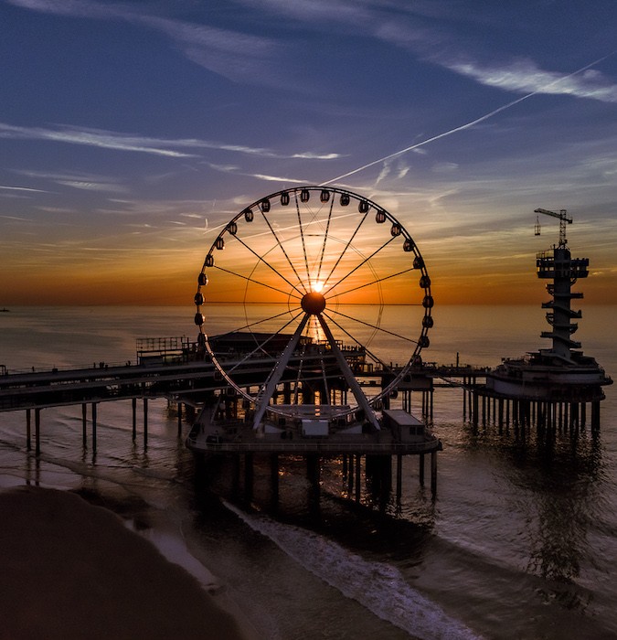 A ferris wheel at the beach during sunset.  