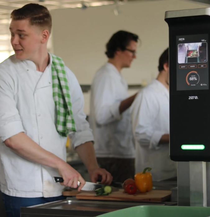 A man preparing food in the kitchen and the product of the startup Orbisk to avoid food waste. 